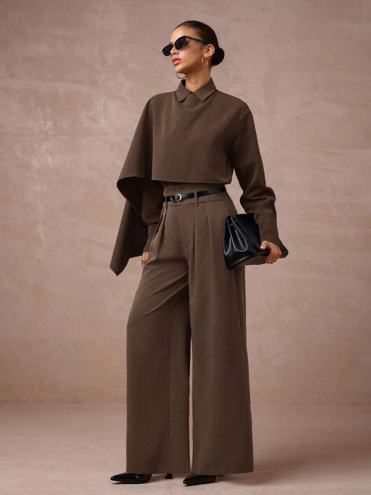 Completo marrone sartoriale con top cropped a collo camicia, pantaloni palazzo e cintura, look minimalista sofisticato.
