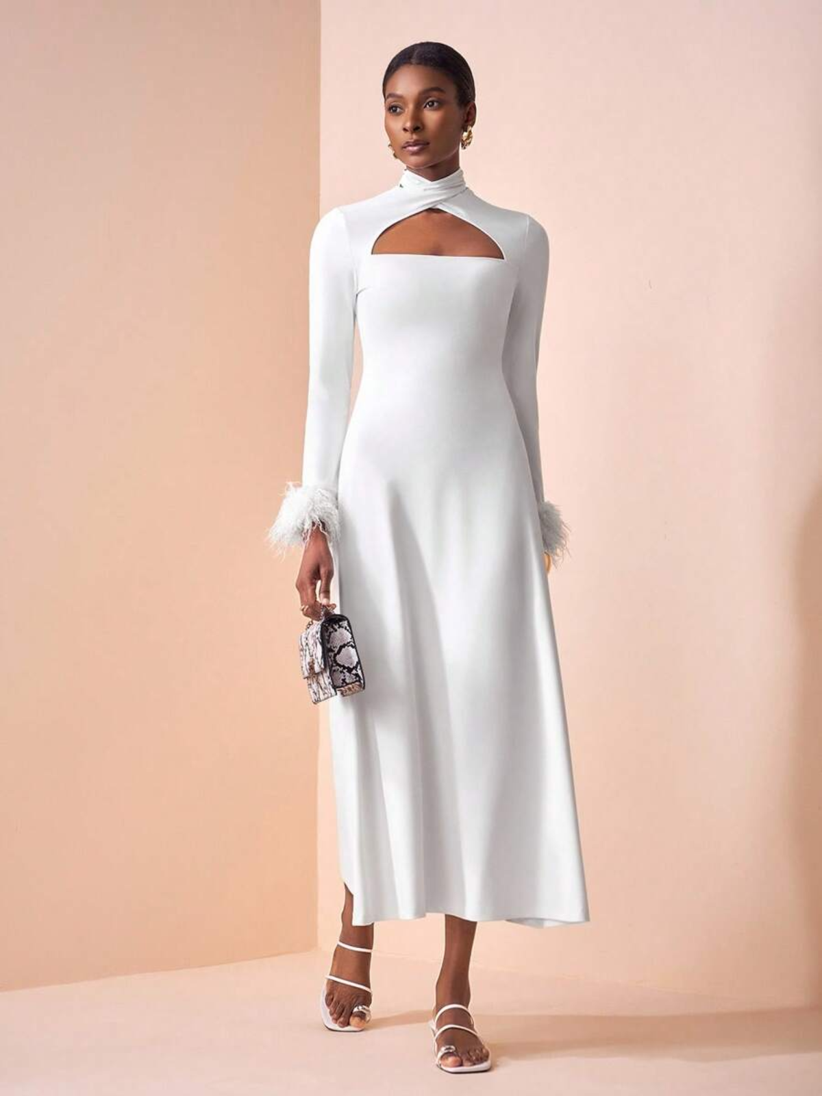 Abito midi elegante con apertura frontale e dettagli in piume, modella con clutch gioiello e sandali con tacco basso, look da cerimonia sofisticato.
