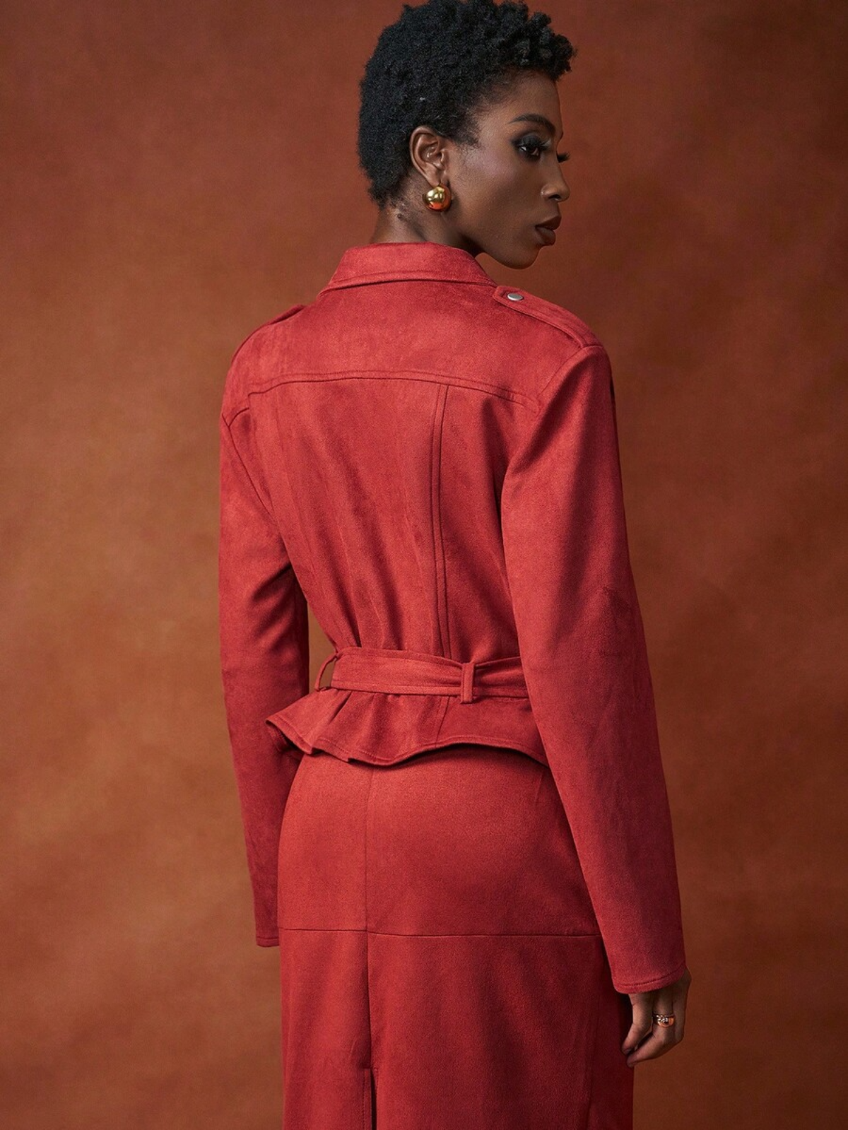 Dettaglio posteriore giacca rossa con cintura regolabile in vita, taglio sartoriale che valorizza la silhouette, gonna midi coordinata.
