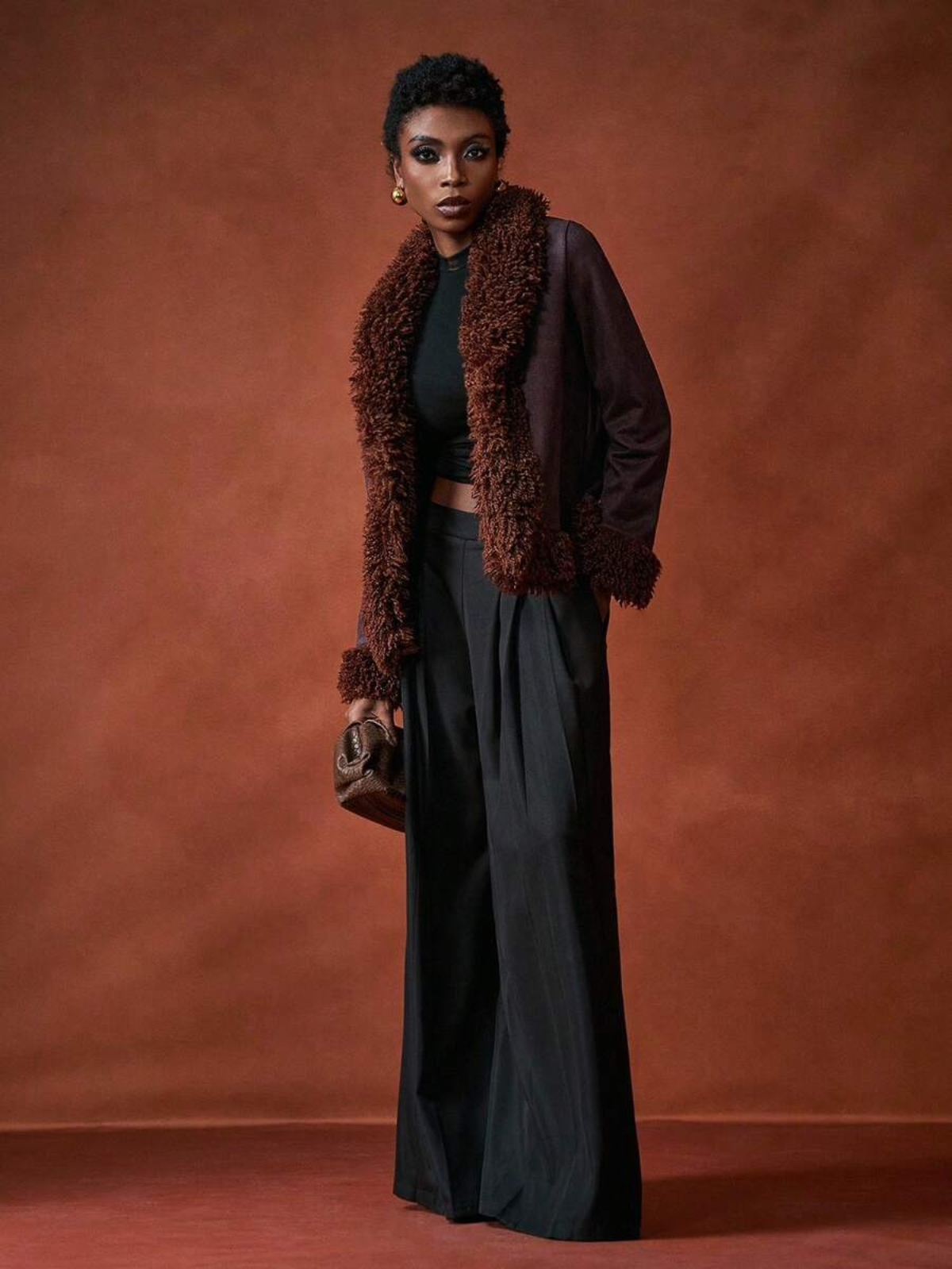 Donna che indossa giacca elegante con dettagli testurizzati e pantaloni , posa sicura per look da sera"