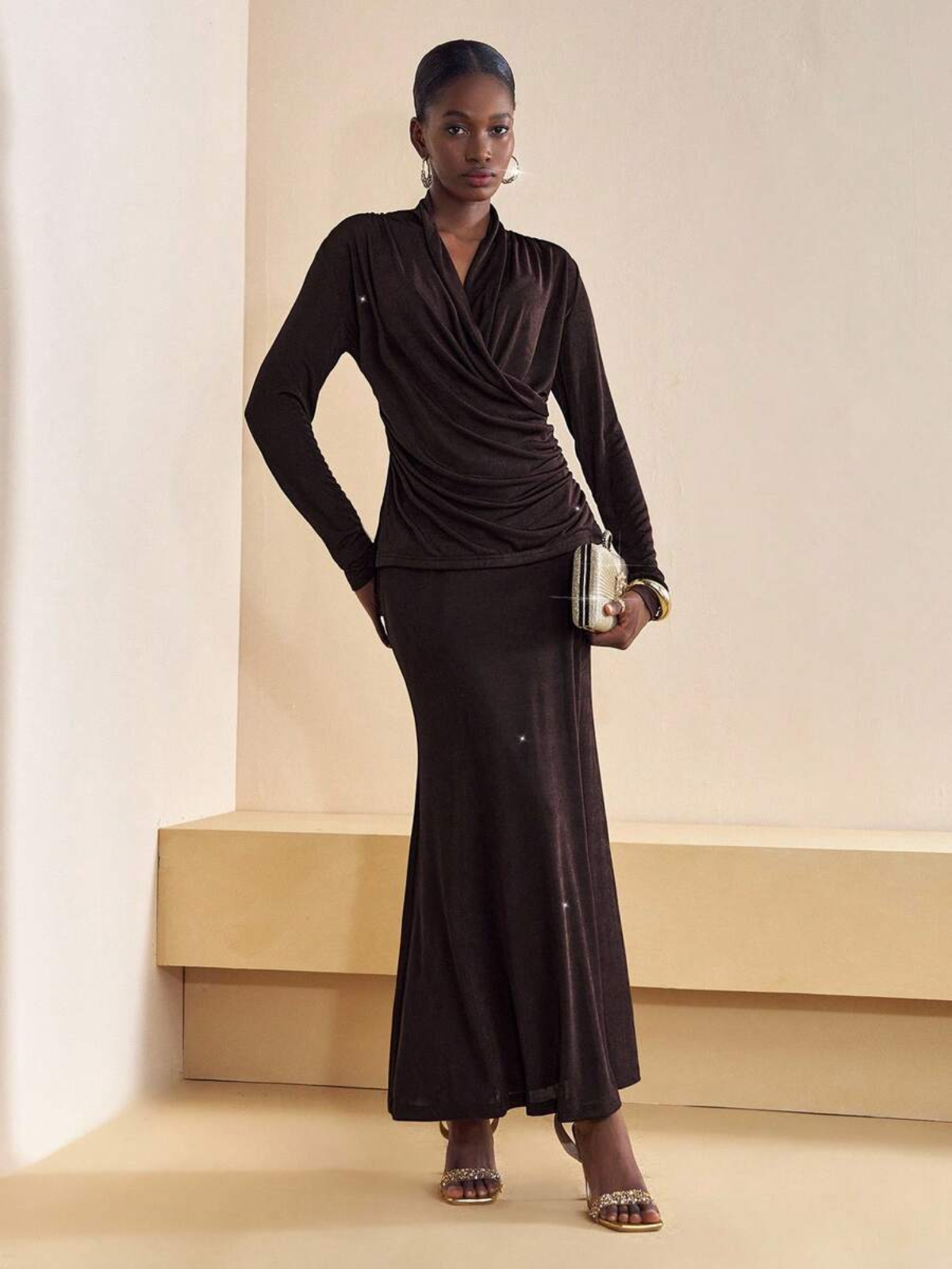 Dettaglio abito marrone con scollo a V avvolgente, tessuto con brillantini discreti, styling elegante per occasioni speciali.
