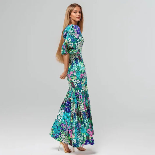 Vestito lungo floreale multicolor con maniche a sbuffo, stampa vivace blu verde viola, su sfondo neutro
